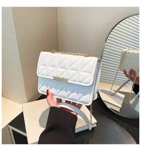Detailed close-up of white quilted crossbody bag with gold chain and metal buckle closure