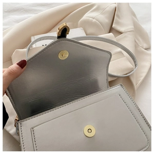 Detail of light grey square bag showing metallic lining and gold magnetic closure