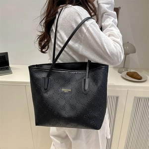 Stylish black large capacity tote bag with embossed flower patterns and a gold logo plate.
