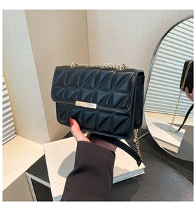 Close-up of a black quilted shoulder bag with gold metal lock and chain strap