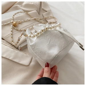 Detailed view of white floral jacquard bucket bag with pearl handle and chain strap