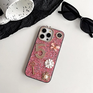 Close-up detail of iPhone glitter case with rhinestone number 5 and butterfly charms.
