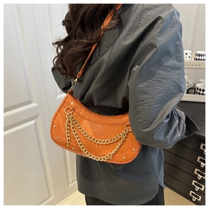 Detail of orange crocodile pattern shoulder bag with gold chain and rivet accents