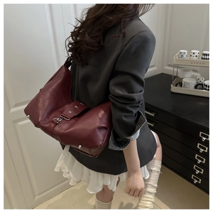 Side view of a vintage wine red leather crossbody bag with silver star rivet details