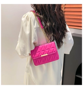 Detail of rose red shoulder bag featuring triangle quilted texture and gold metal chain