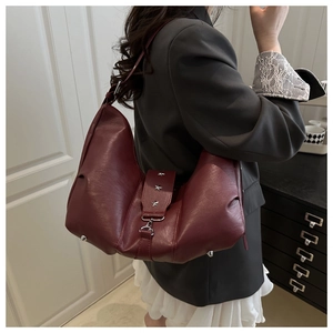 Detail of burgundy half-moon crossbody bag featuring silver star rivets and metal clasp