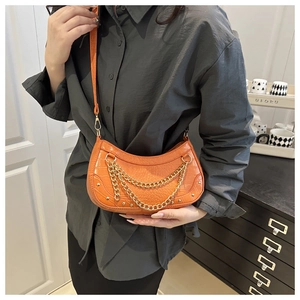 Close-up of orange crescent crossbody bag with faux crocodile texture and gold chain