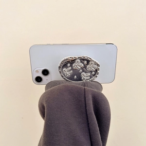 Detail shot of a silver butterfly embossed phone socket grip on a white smartphone