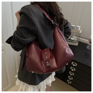 Detail view of burgundy leather crossbody bag with silver star studs on model's side
