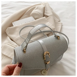 Detail of silver textured woven handbag with gold hardware and grey leather strap