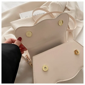 Détail d'un sac bandoulière beige crème avec rabat oreilles de chat et boutons aimantés