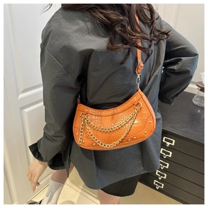 Close-up of orange crescent bag with golden chain detail and croc-embossed texture