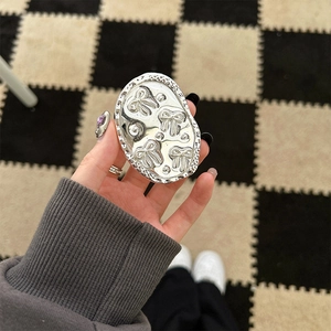 Detailed view of silver oval phone grip with embossed bows and hammered metal texture