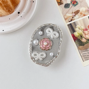 Détail du support téléphone avec camélia rose, perles et ornements de papillon