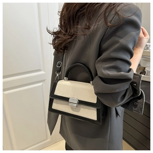 Detail of contrast stitching textured square bag with silver clasp and black leather handle