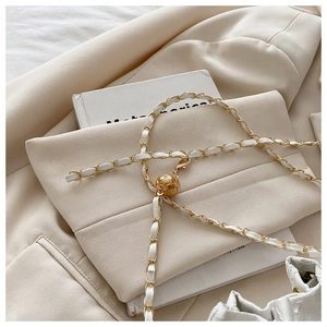 Detail of woven white leather chain with a gold quilted adjustable ball buckle
