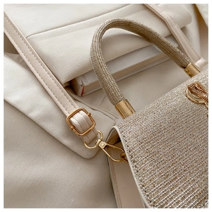 Détail du sac à main crème pailleté avec accessoires dorés et bandoulière réglable