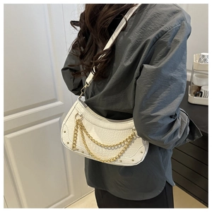 Detail view of white crocodile pattern crescent bag with gold chain and metal studs