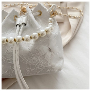 Detail of white bucket bag featuring 3D butterfly appliques and pearl handle