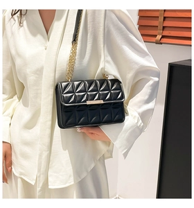 Detail of black quilted leather crossbody bag with gold chain strap and metal buckle