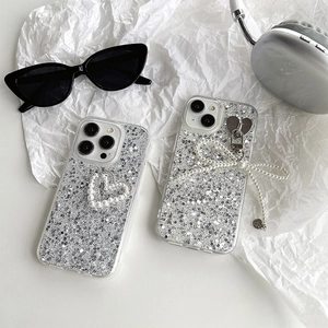 Close-up of silver glitter iPhone case featuring pearl bow and heart pendant details