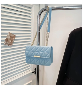 Detail of light blue quilted shoulder bag featuring gold hardware and chain strap
