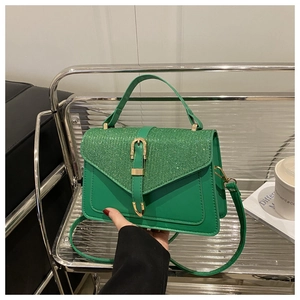 Detail of green crossbody bag showing glitter patchwork and golden metal buckle