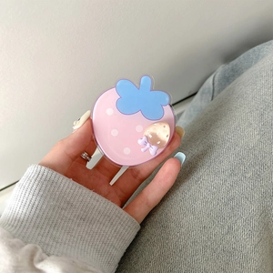 Close-up of a pink strawberry phone socket stand with 3D acrylic charms held by hand
