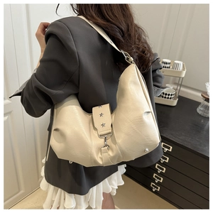 Detail of cream leather shoulder bag featuring stylish silver star studs on the side strap