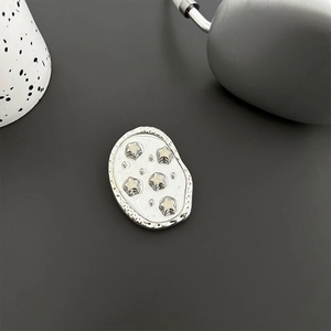 Macro shot of silver irregular pebble phone grip with embossed star patterns and polished finish