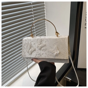 Close-up of white lace floral fabric and 3D butterfly embroidery on elegant handbag