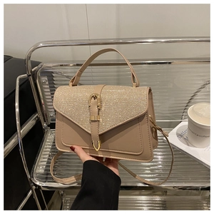 Close-up of beige sequined flap bag with golden buckle and detachable shoulder strap