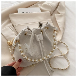 Detail of white lace bucket bag with large pearl handle and mesh flower accent