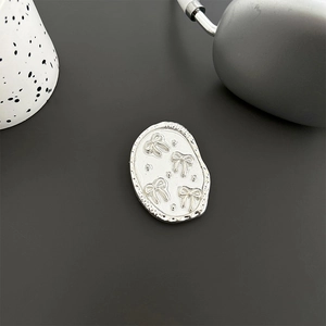 Macro detail of oval silver phone grip with white enamel finish and bow relief pattern