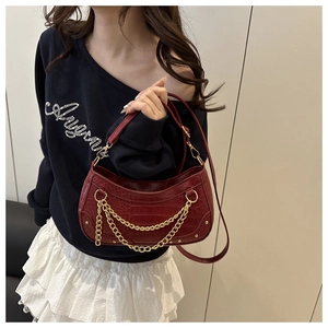 Close-up of retro burgundy faux crocodile leather shoulder bag with gold chain accents