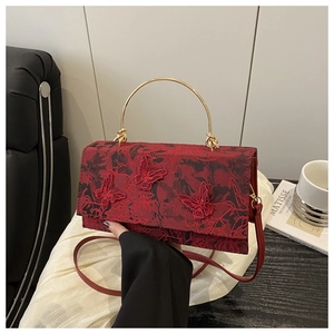 Detail of red crossbody bag with butterfly embroidery and golden circular handle