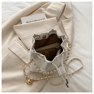 Detail of jacquard bucket bag showing spacious interior with pearl handle and chain strap