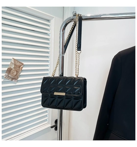 Close-up of black quilted shoulder bag with gold metal clasp and chain strap detail