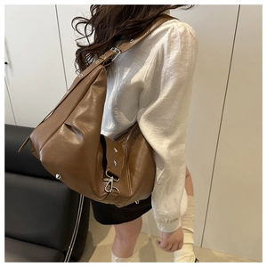 Detail of wide strap with silver buckles and star rivets on a brown hobo bag