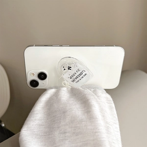Cute bear acrylic phone grip stand on a white smartphone against a cozy knit background