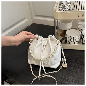 Close-up of white lace bucket bag featuring pearl handle and drawstring closure