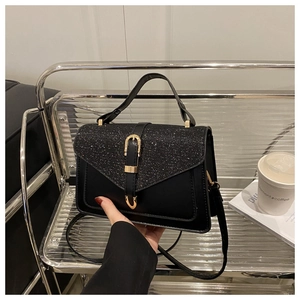 Detail of black sequined handbag with gold buckle decoration and leather strap