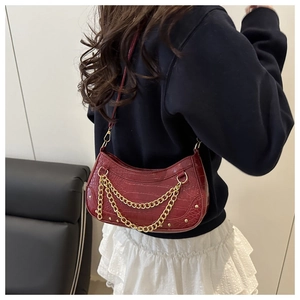 Sac demi-lune bordeaux avec motif crocodile et chaînes dorées porté sur l'épaule