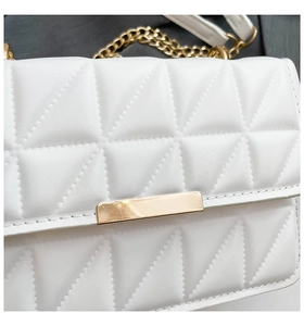 Detail of white quilted handbag with triangle texture and gold metal rectangle clasp