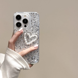 Close-up of glitter iPhone case with pearl bow and heart decoration held in hand