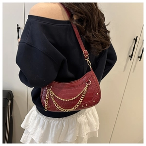 Détail du sac baguette rouge foncé effet crocodile avec chaîne dorée et clous