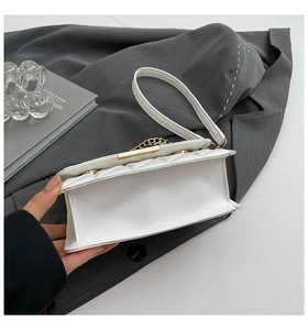 Detailed close-up of white quilted PU leather handbag with gold chain and reinforced base