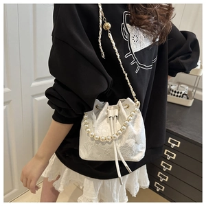 Close-up of a white lace bucket bag with 3D butterfly decor and pearl handle