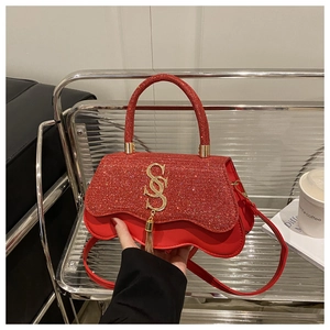 Détail du rabat pailleté rouge et boucle dorée en S avec pompon sur un sac à main