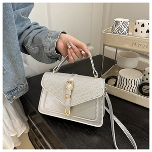 Detail of silver-grey leather handbag with textured flap and golden metal buckle